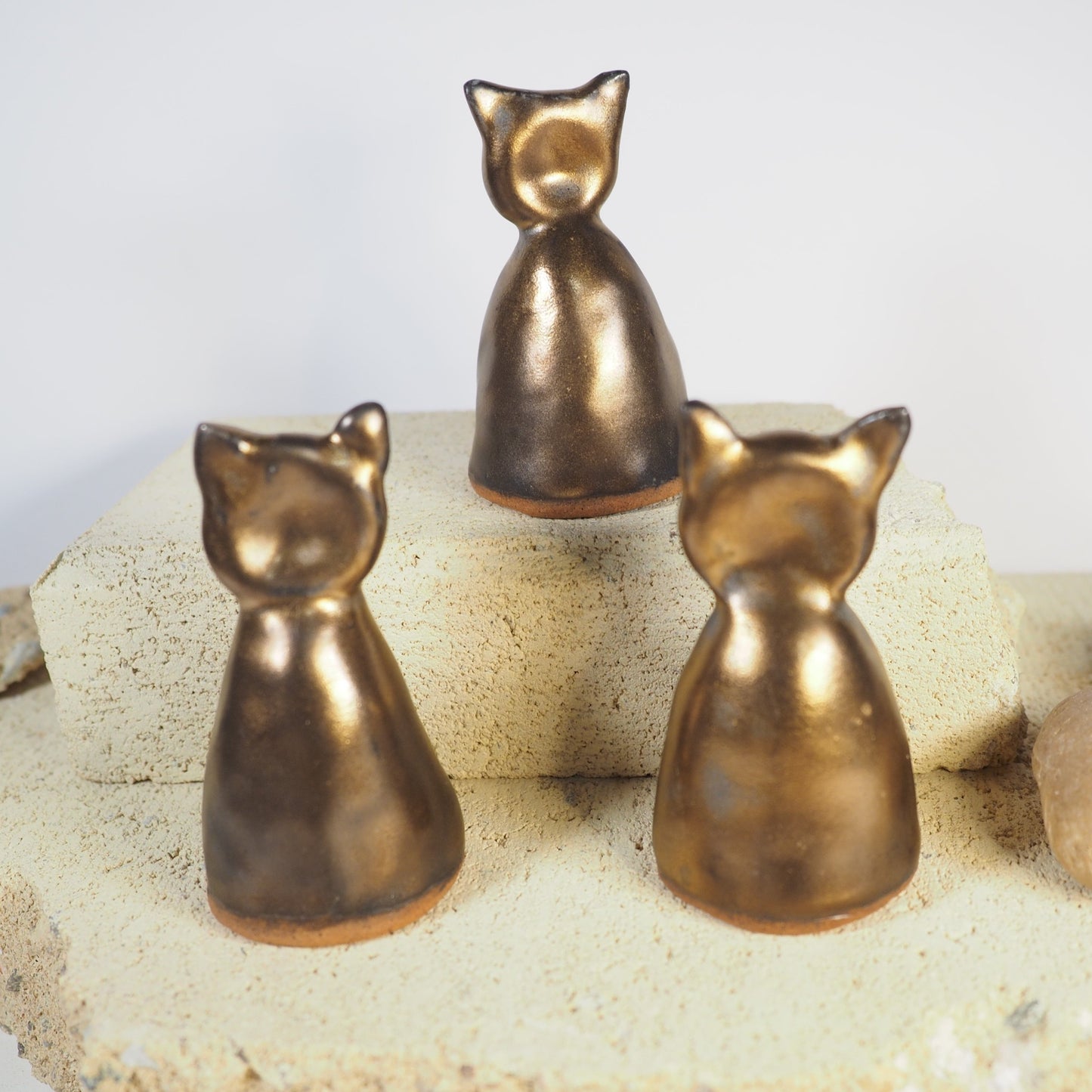 Candle snuffers in gold ceramic ware in cat shape.