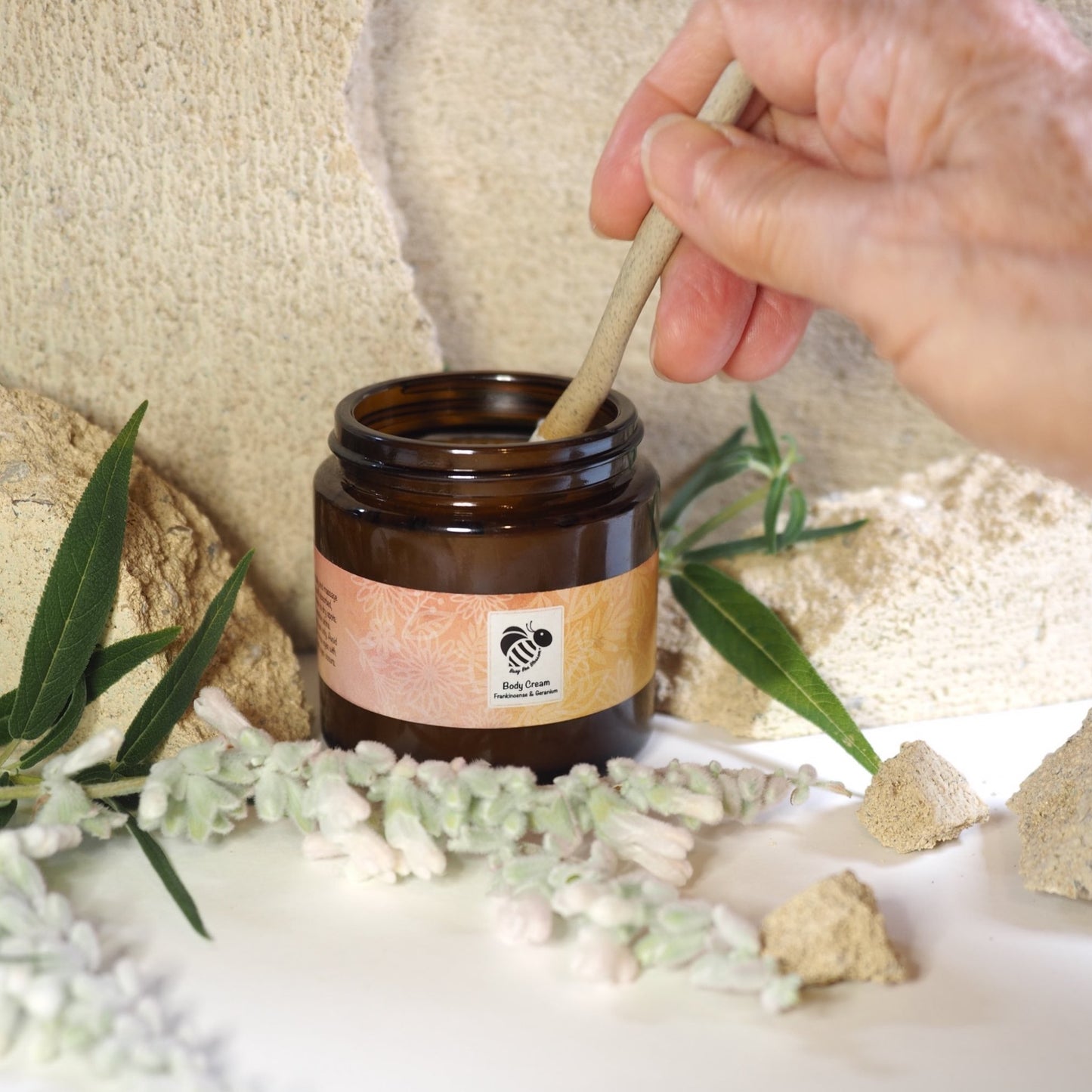 Frankincense and Geranium Repair Body Cream with hands holding ceramic spoon