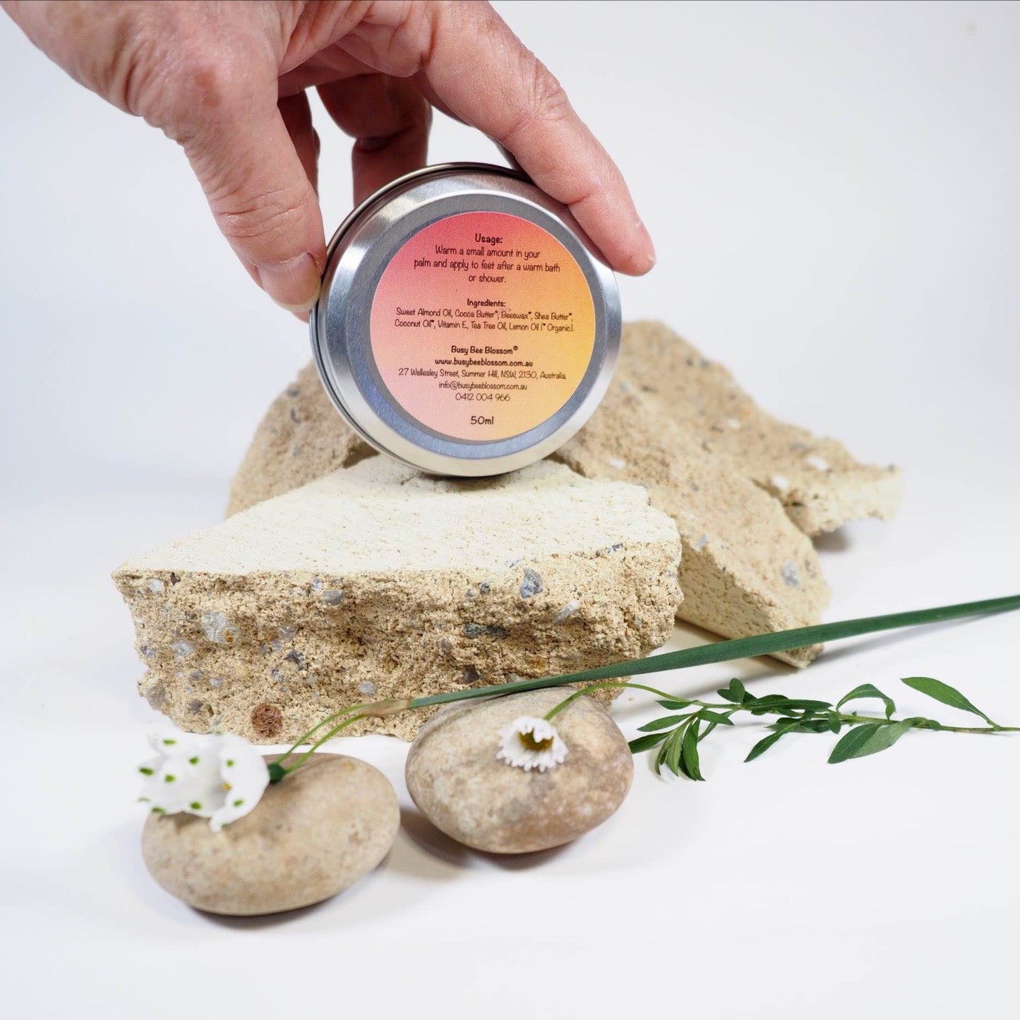 Tea Tree and Lemon Foot Balm held in my hands showing the underside of tin