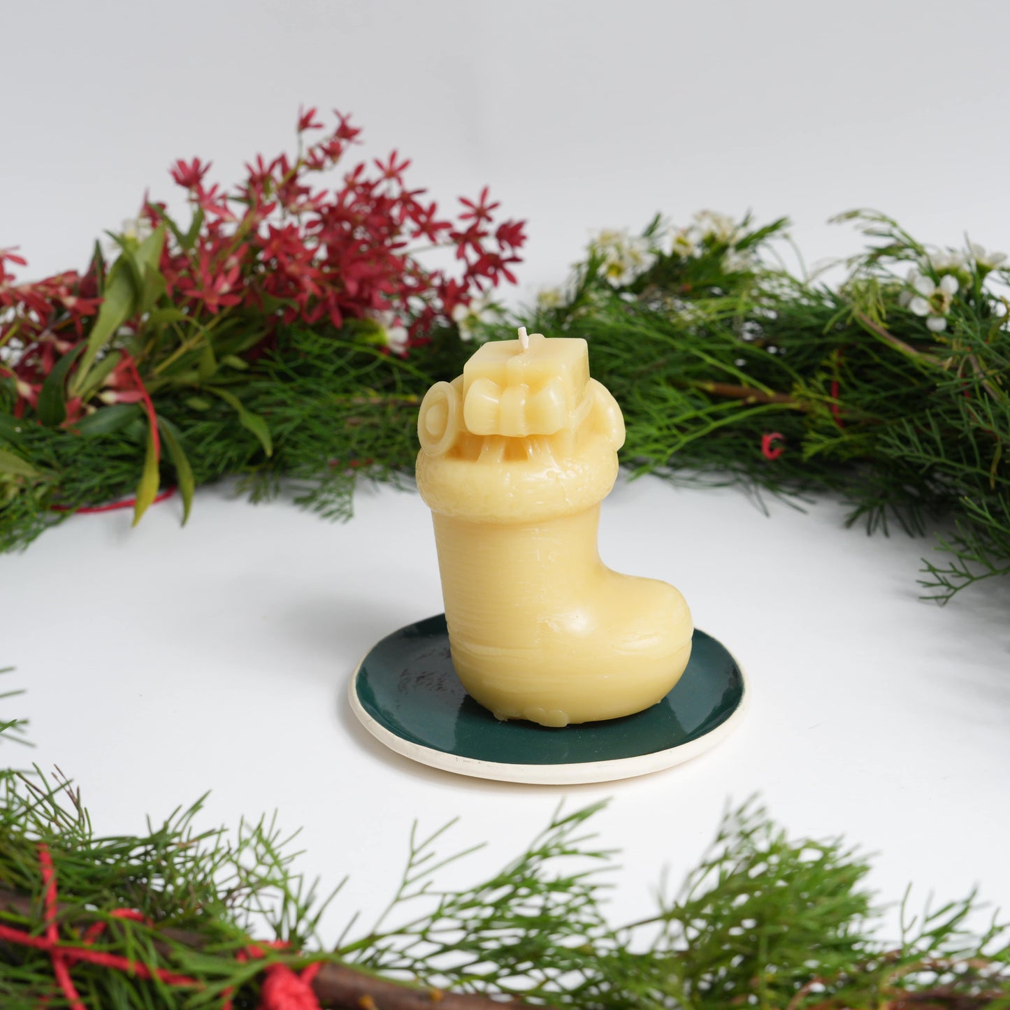Christmas stocking beeswax candle on green plate with a Christmas wreath