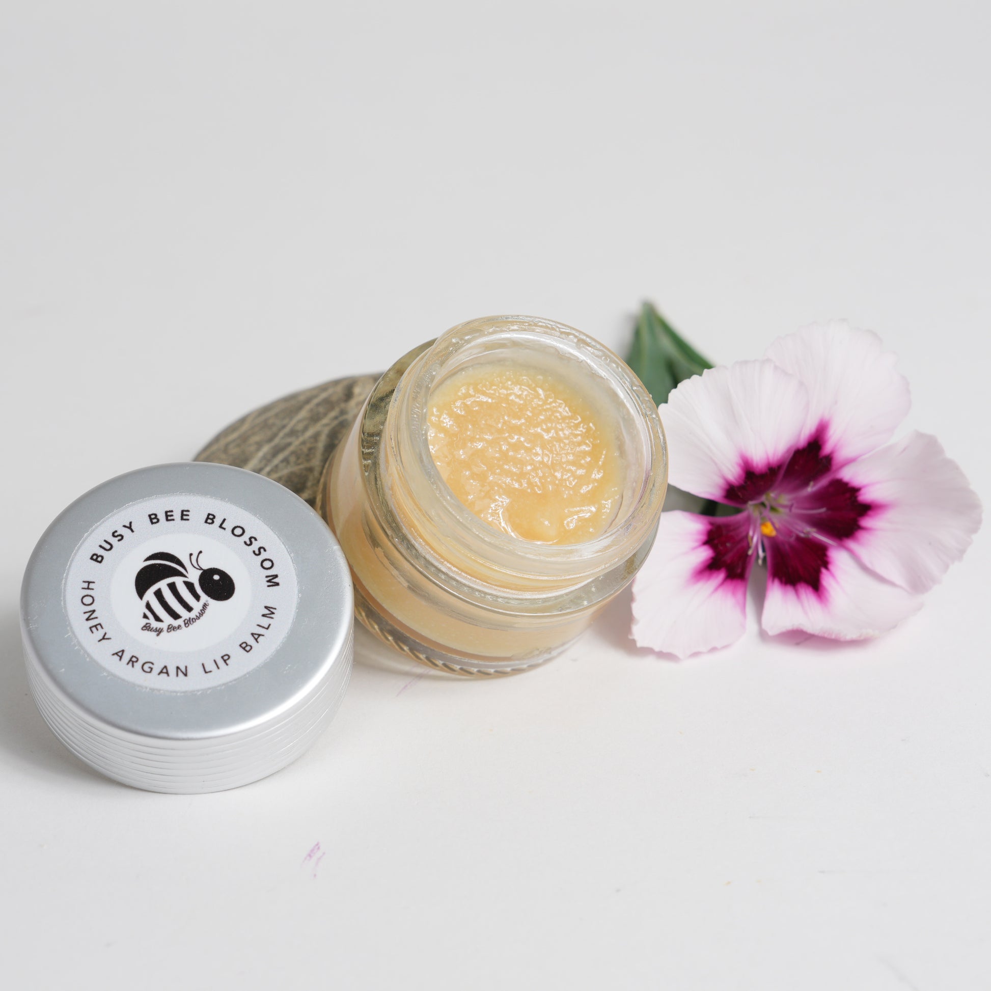 Honey Argan Lip Balm opened with lid to one side and flower