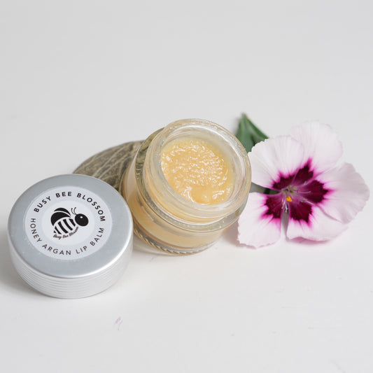Honey Argan Lip Balm opened with lid to one side and flower