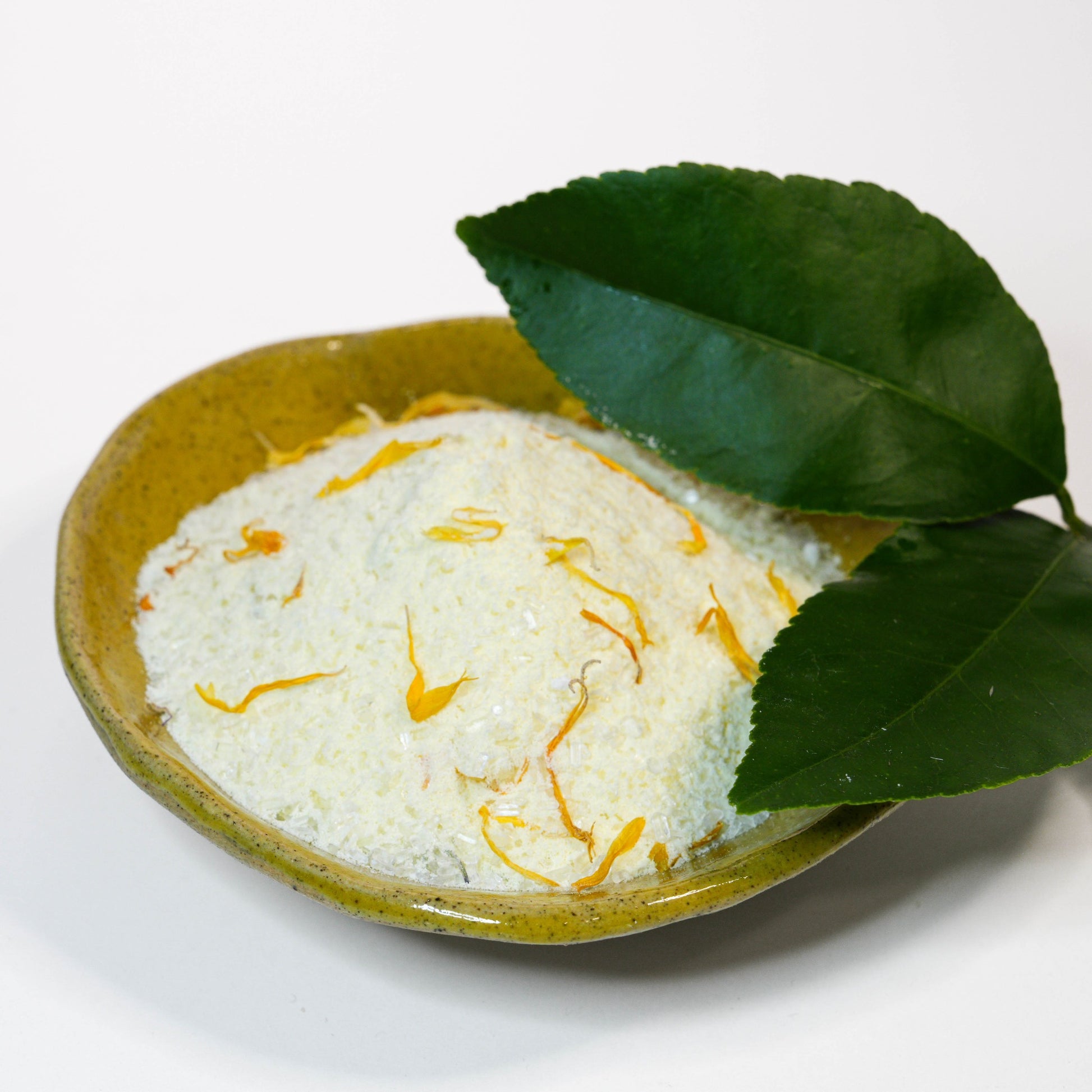 Lemon Calendula Bath Soak in ceramic bowl with lemon leaves