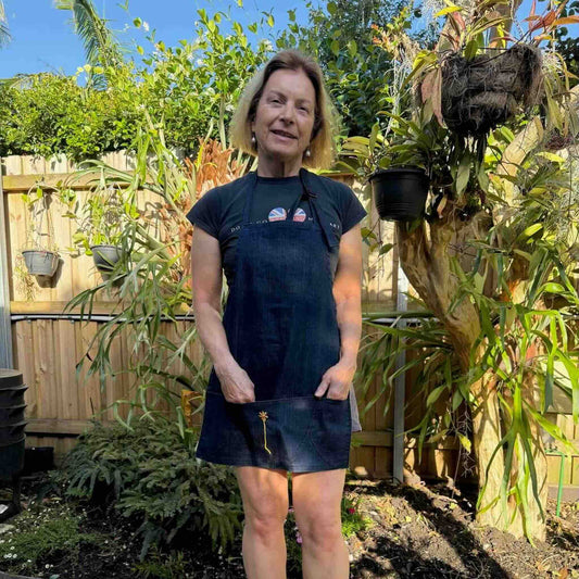 Louise wearing denim apron with embroidered calendula flower