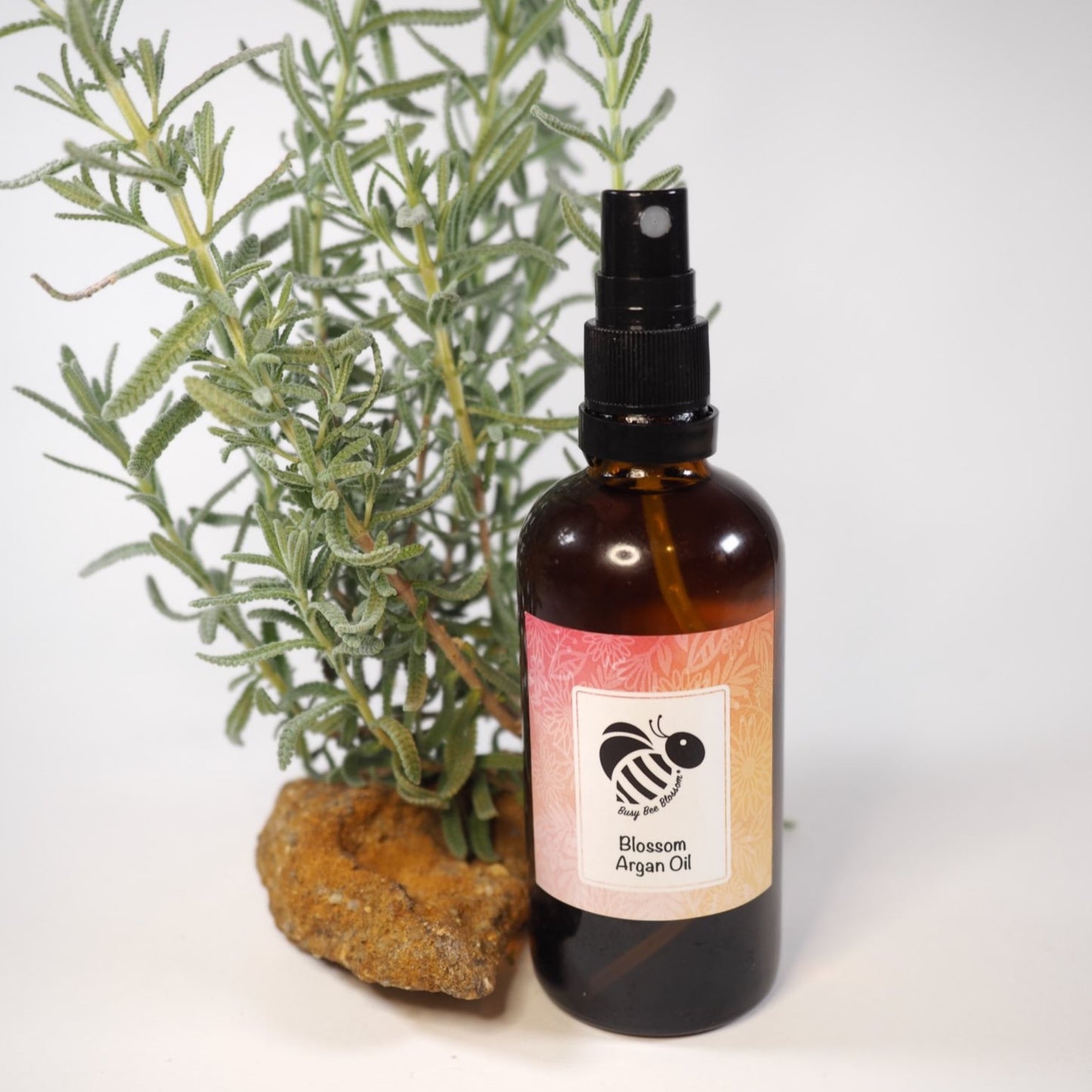 Blossom pure Moroccan Argan Oil with green sprigs in the background.
