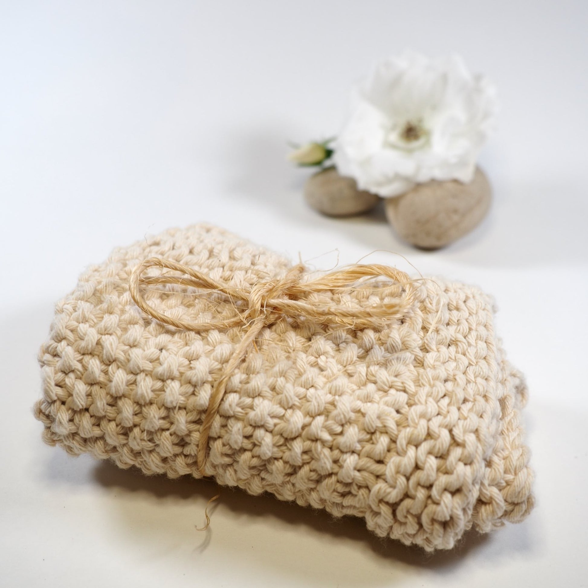 Hand knitted cotton face cloth tied with string with rock and rose. Provides gentle cleansing and exfoliation every day.