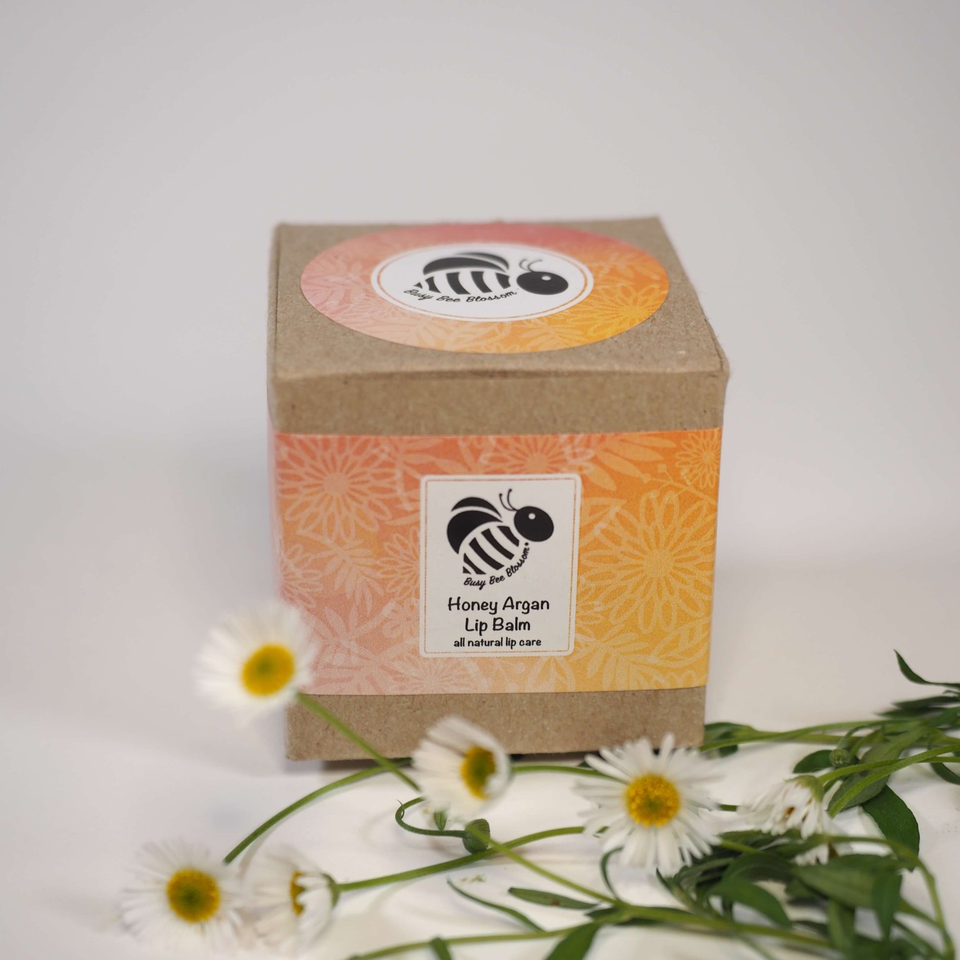 Honey Argan Lip Balm packaging and daisies
